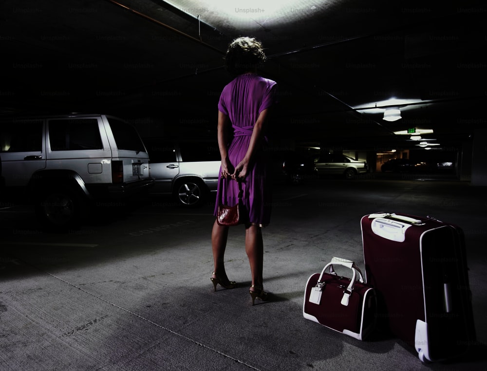 a woman standing in a parking garage next to luggage