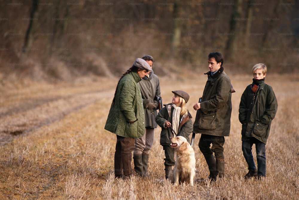 a group of people standing in a field with a dog
