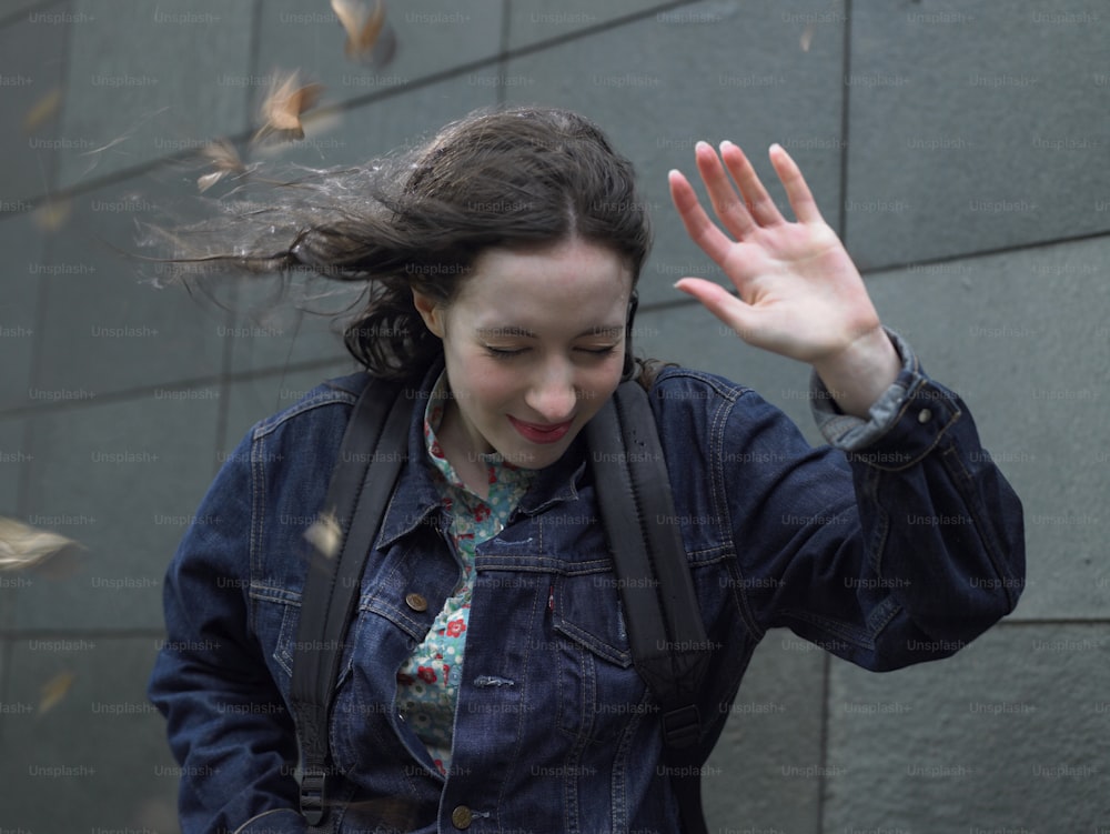 a woman in a jean jacket is waving her hands