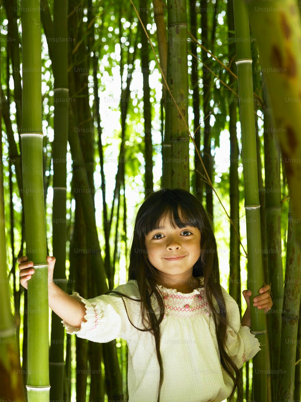 a little girl standing in front of a bamboo tree