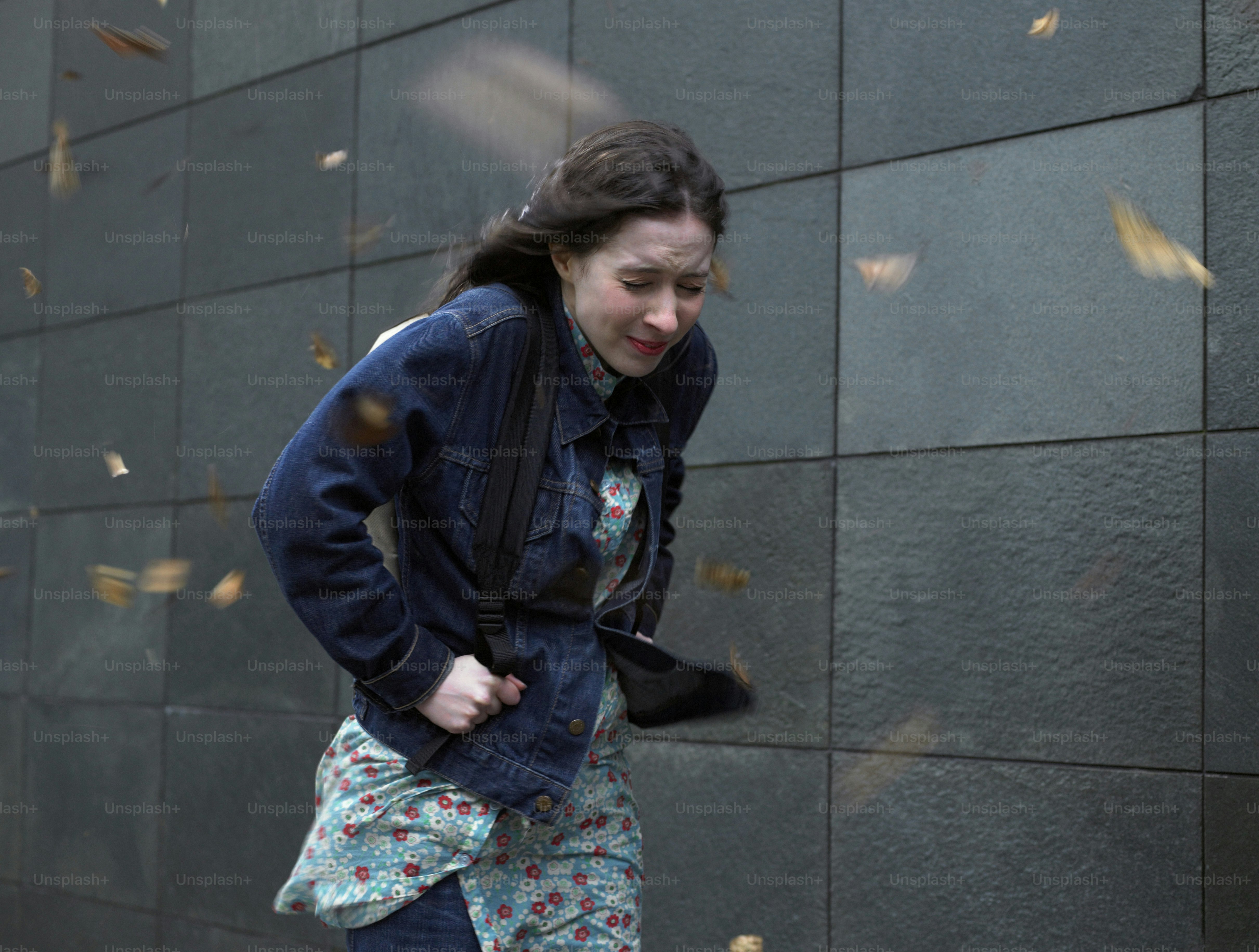 a woman walking down a street next to a wall