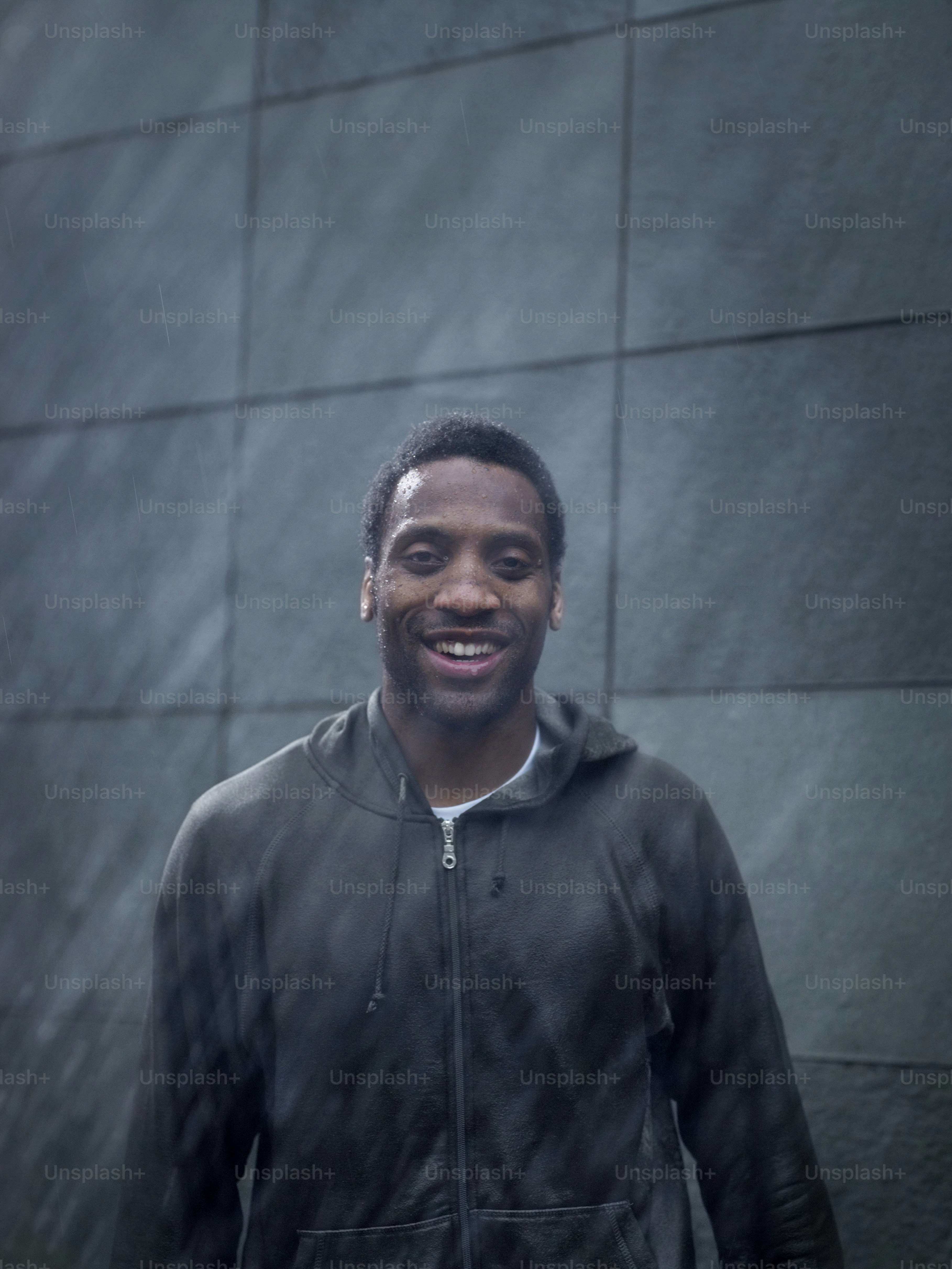 Un uomo in piedi davanti a un muro sotto la pioggia