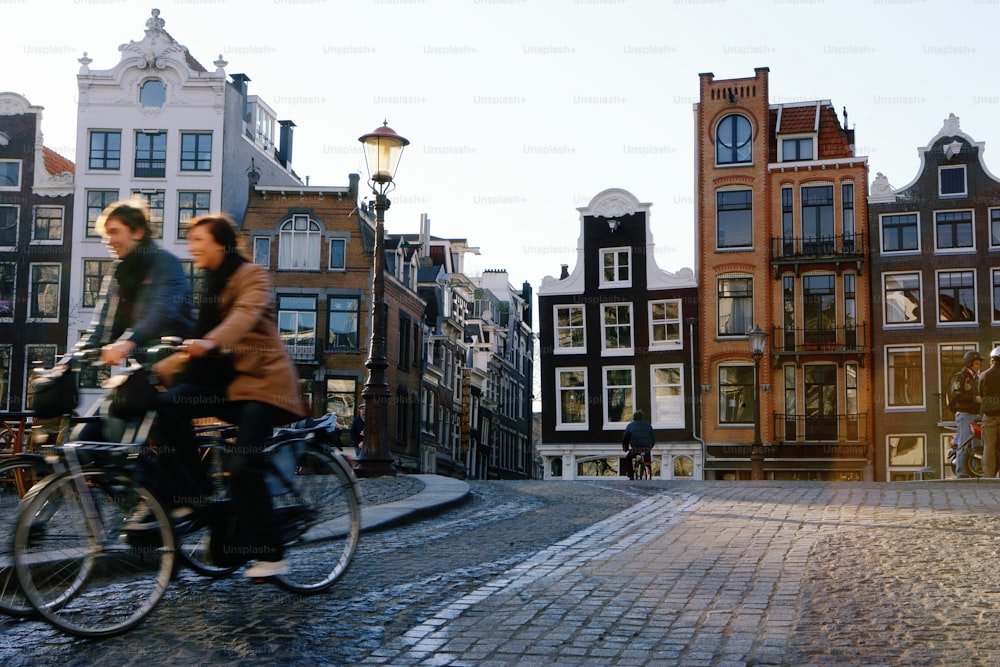 a couple of people riding bikes down a cobblestone street