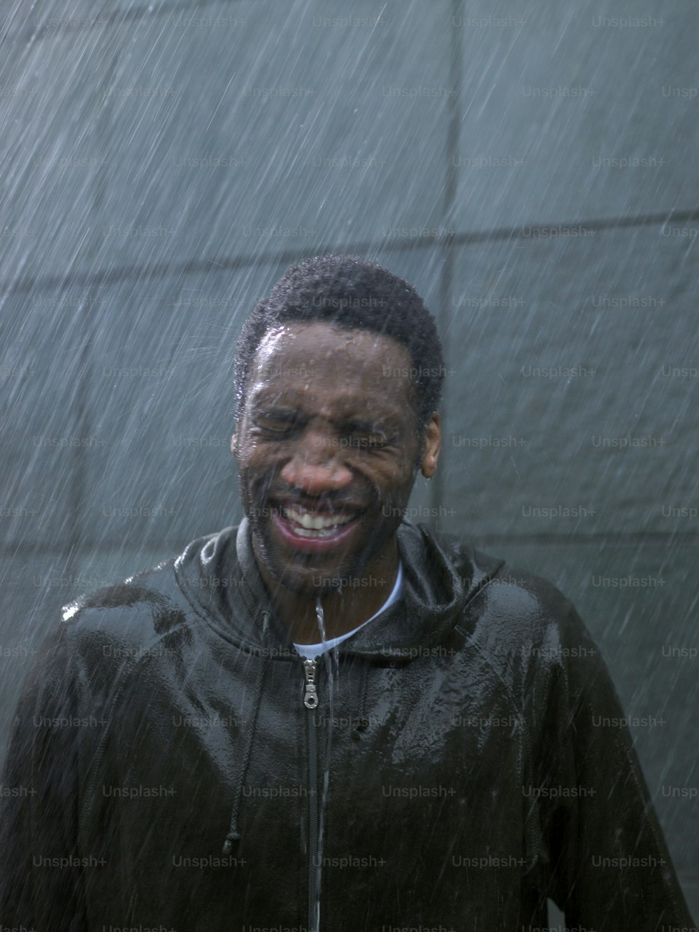 a man smiling while standing in the rain
