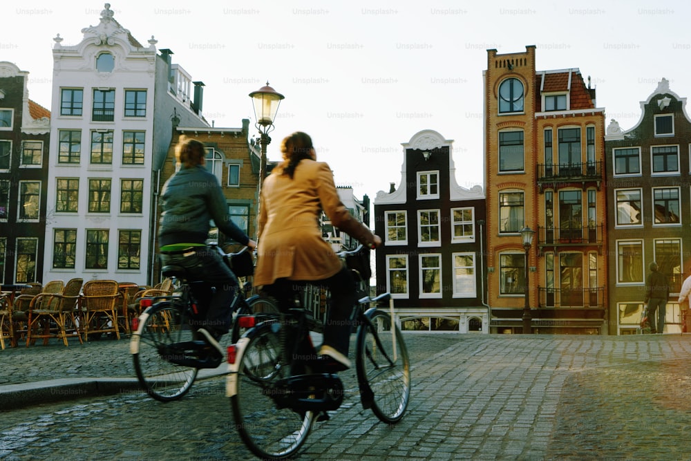 a couple of people riding bikes down a cobblestone road