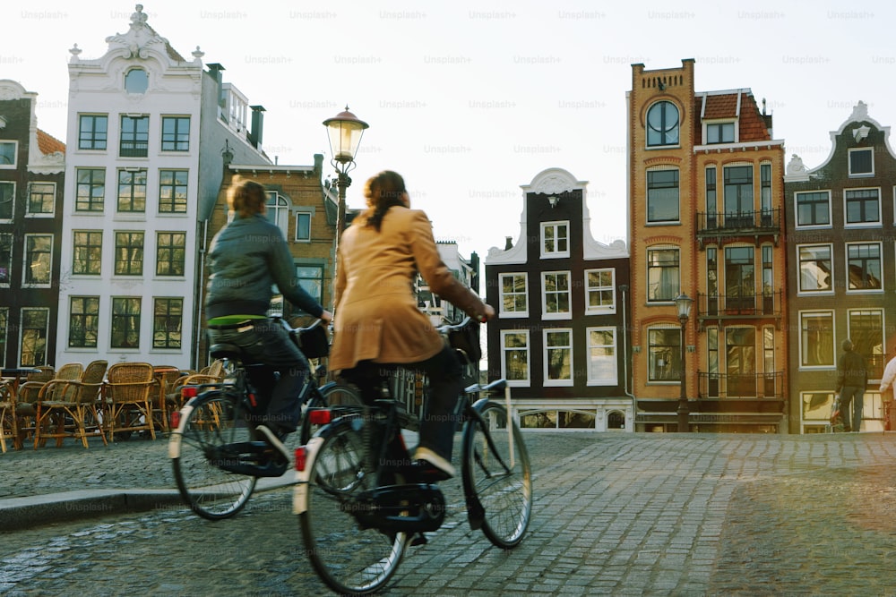 um casal de pessoas andando de bicicleta por uma estrada de paralelepípedos