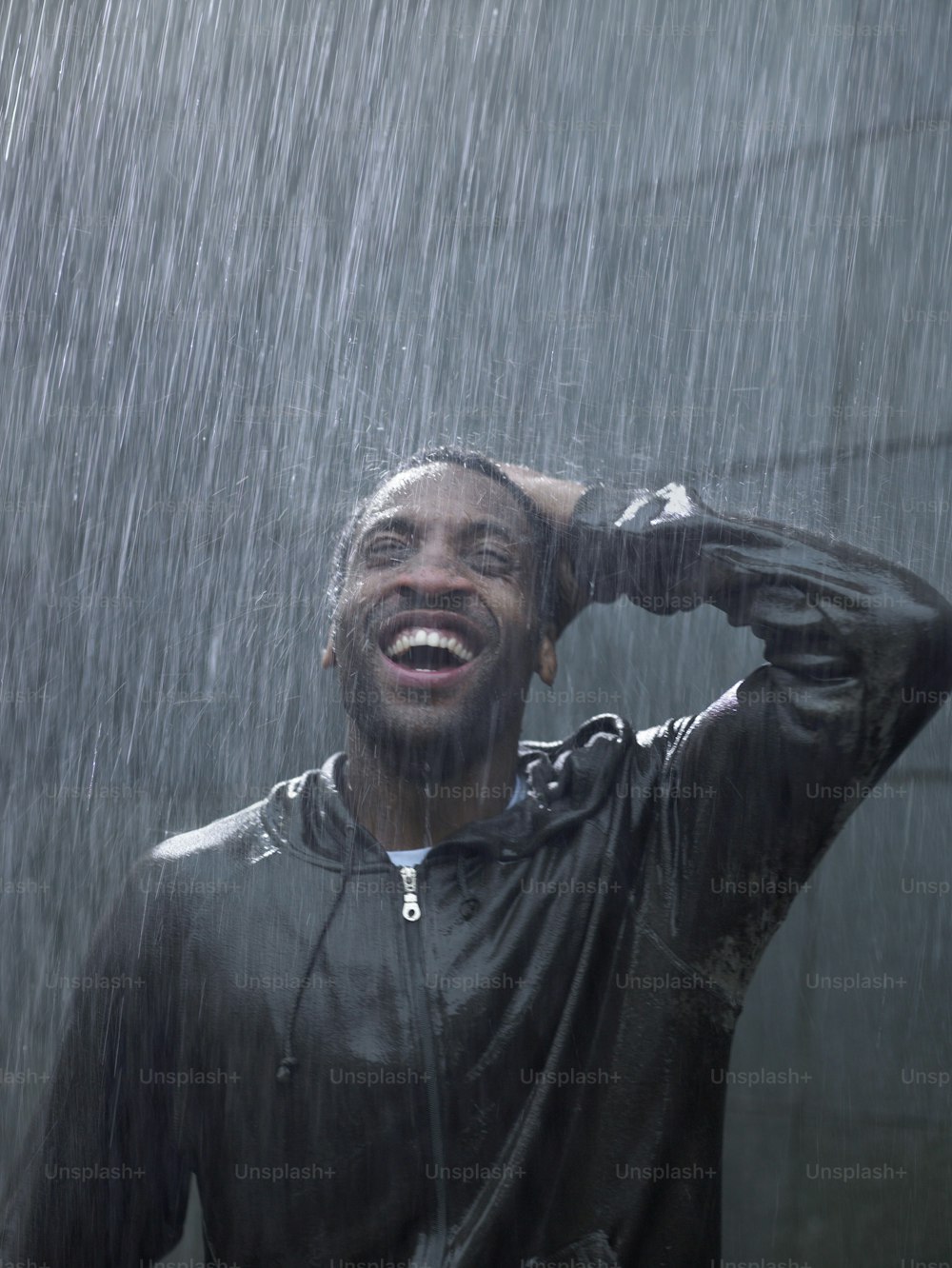 한 남자가 빗속에 서서 웃고 있다