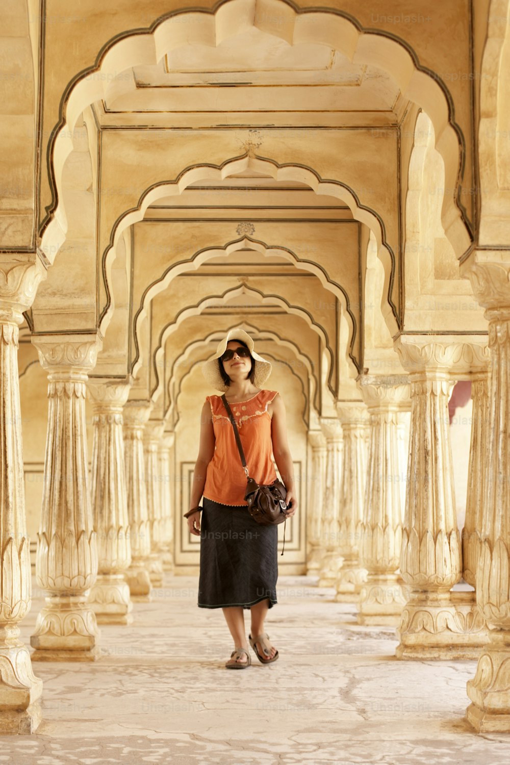 a woman in an orange shirt and black skirt standing in a building