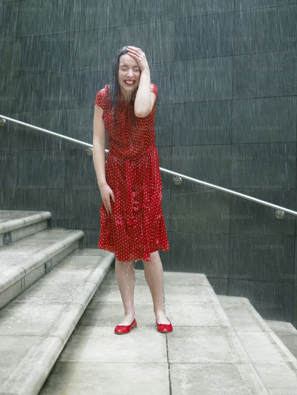 a woman in a red dress standing in the rain