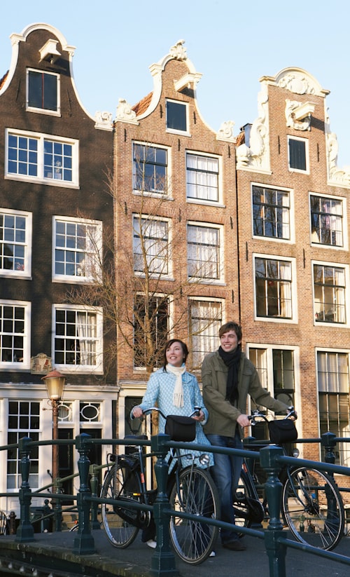 A man and a woman standing next to their bicycles in a lush green park