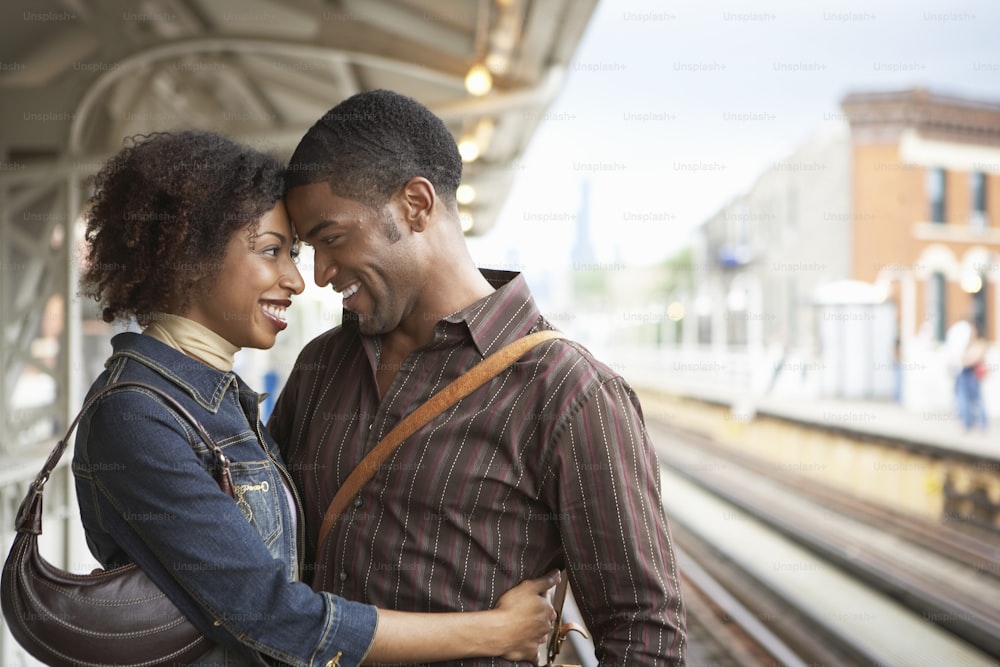 a man and woman standing next to each other near a train station