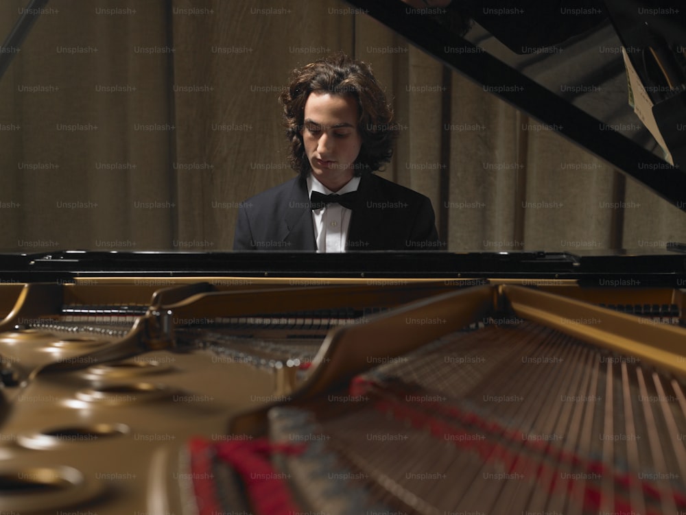 a man in a tuxedo playing a piano
