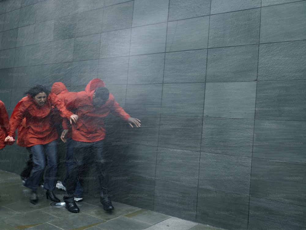 Eine Gruppe von Menschen in roten Jacken steht vor einer Wand
