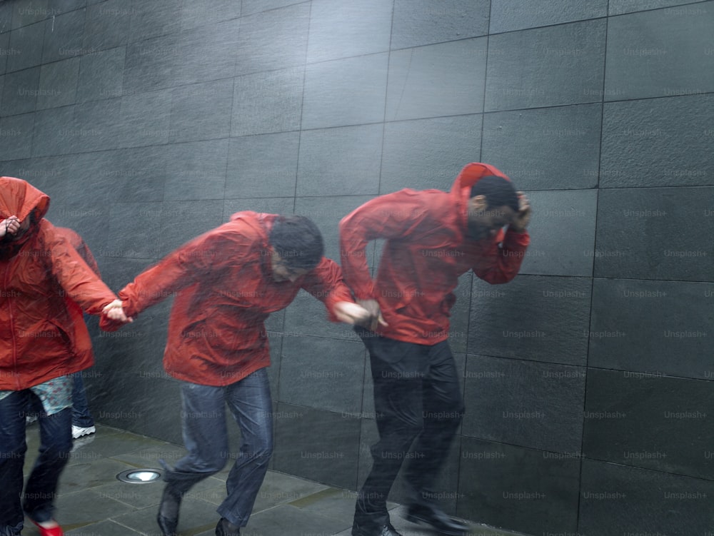 Eine Gruppe von Menschen in roten Jacken, die neben einer Wand stehen