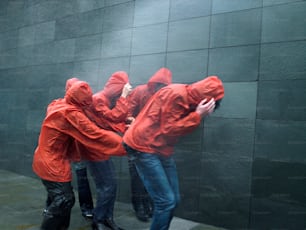 a group of people in red raincoats leaning against a wall