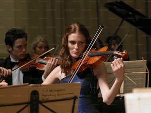 Una mujer con un vestido azul tocando un violín