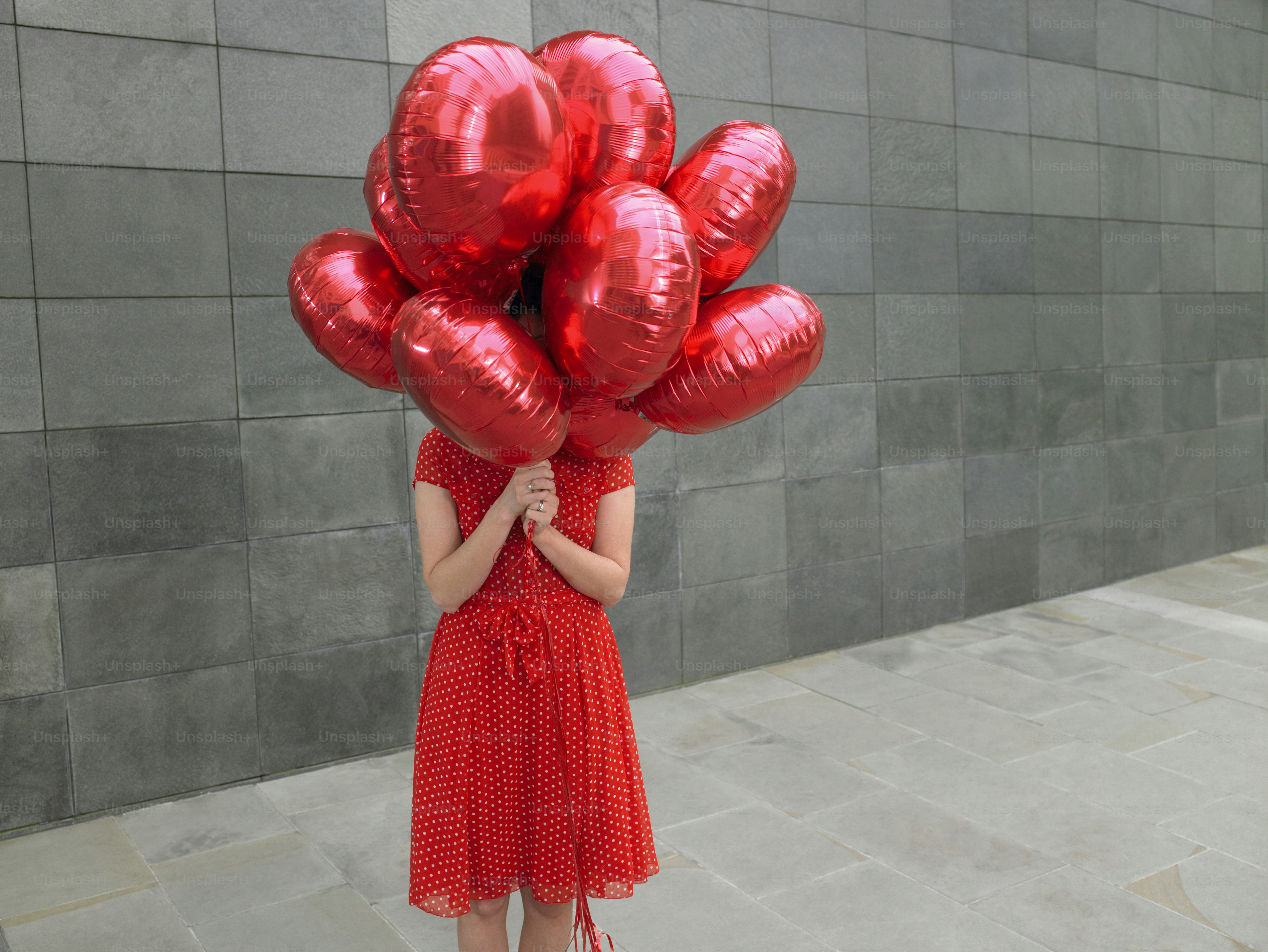 Une femme tenant un bouquet de ballons rouges