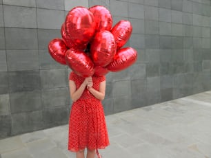 Une femme tenant un bouquet de ballons rouges