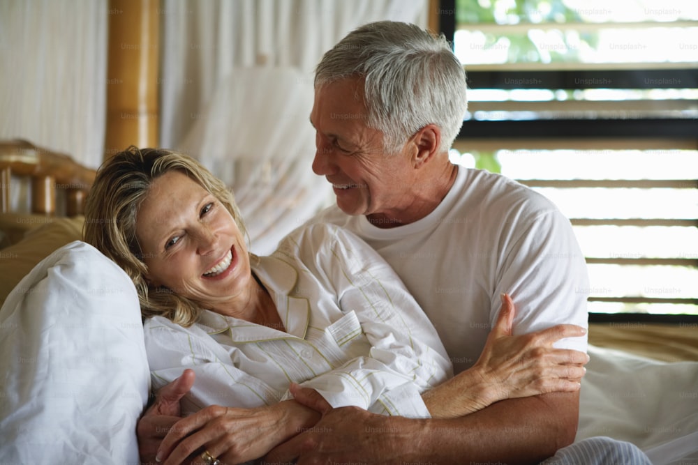 a man and a woman sitting on top of a bed