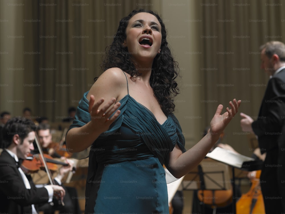 a woman in a green dress standing in front of a orchestra
