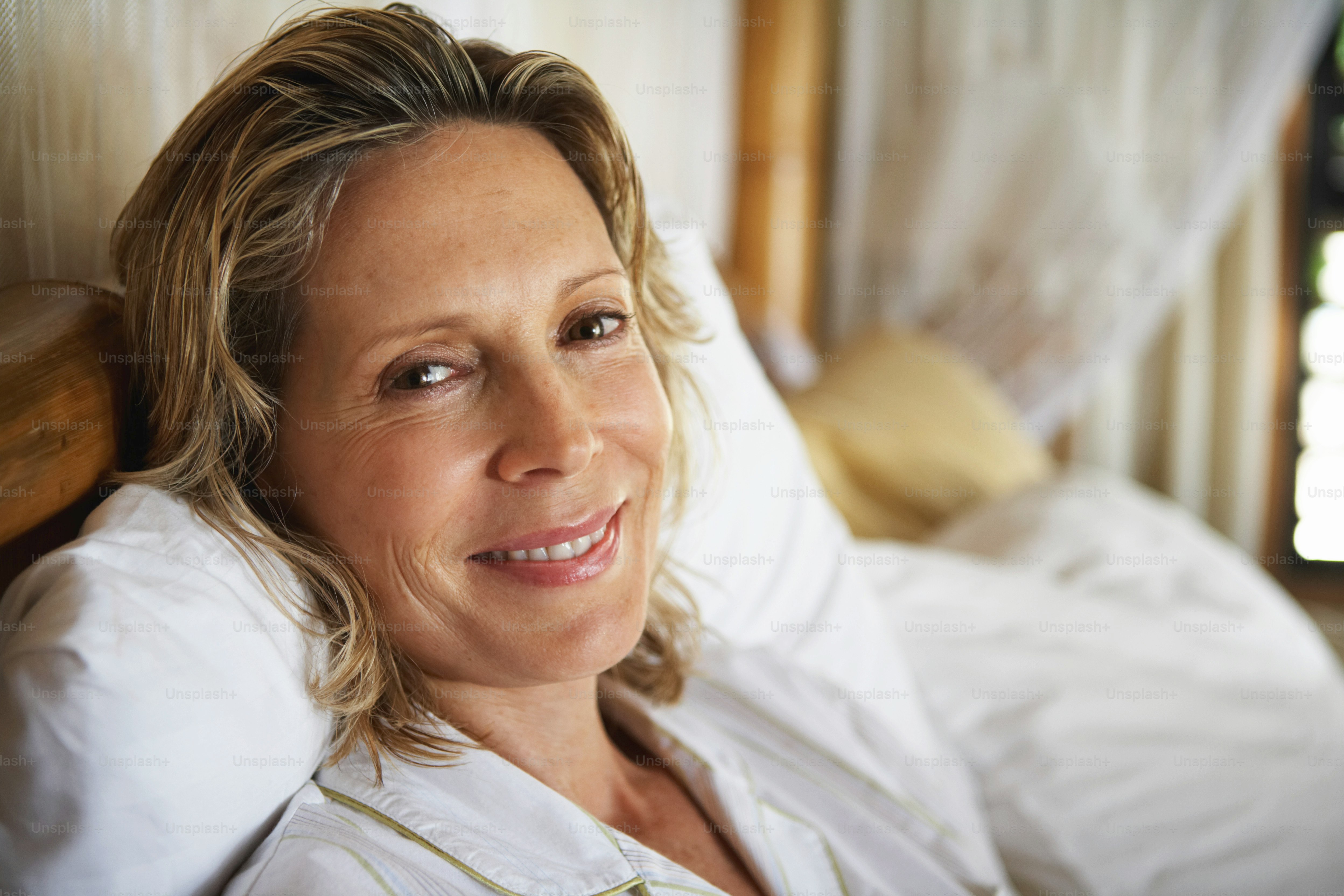 eine frau, die auf einem bett liegt und in die kamera lächelt