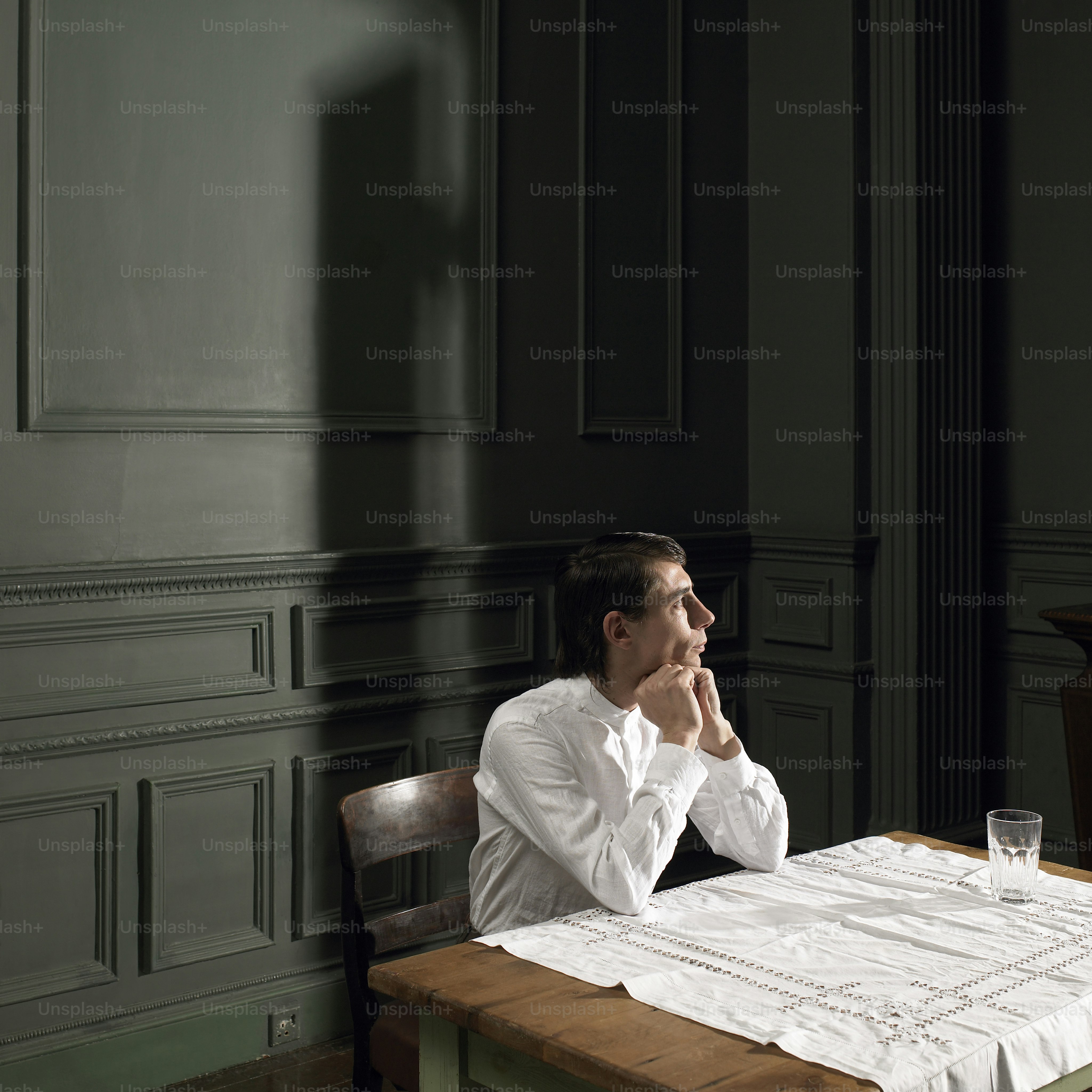 Un hombre sentado en una mesa con un vaso frente a él foto – Imagen de ...