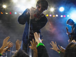 un uomo in piedi sopra un palco con in mano un microfono