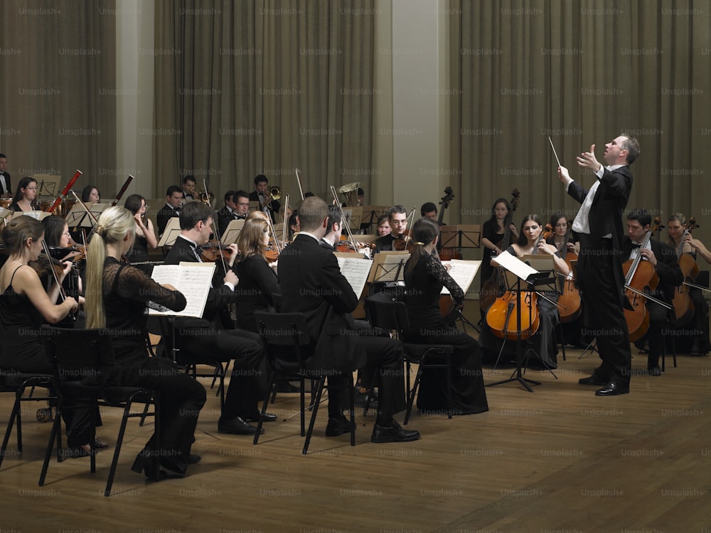 a conductor and orchestra in a large room