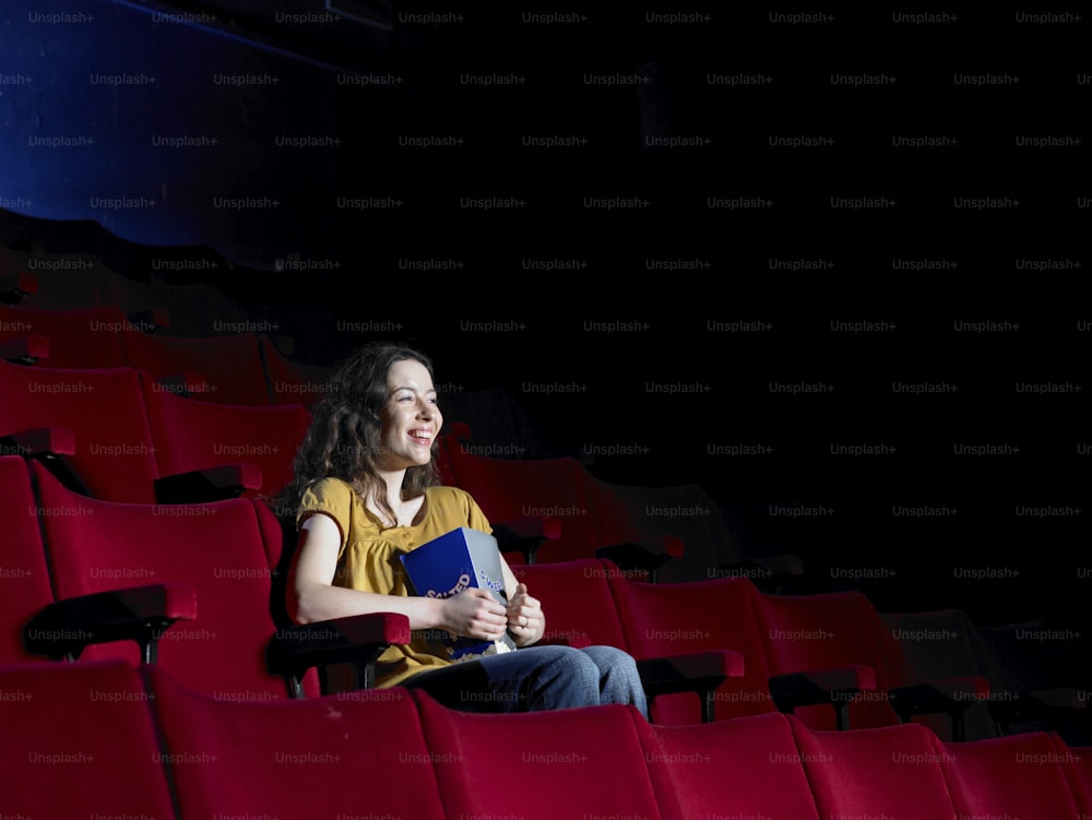 a woman sitting in a theater holding a book
