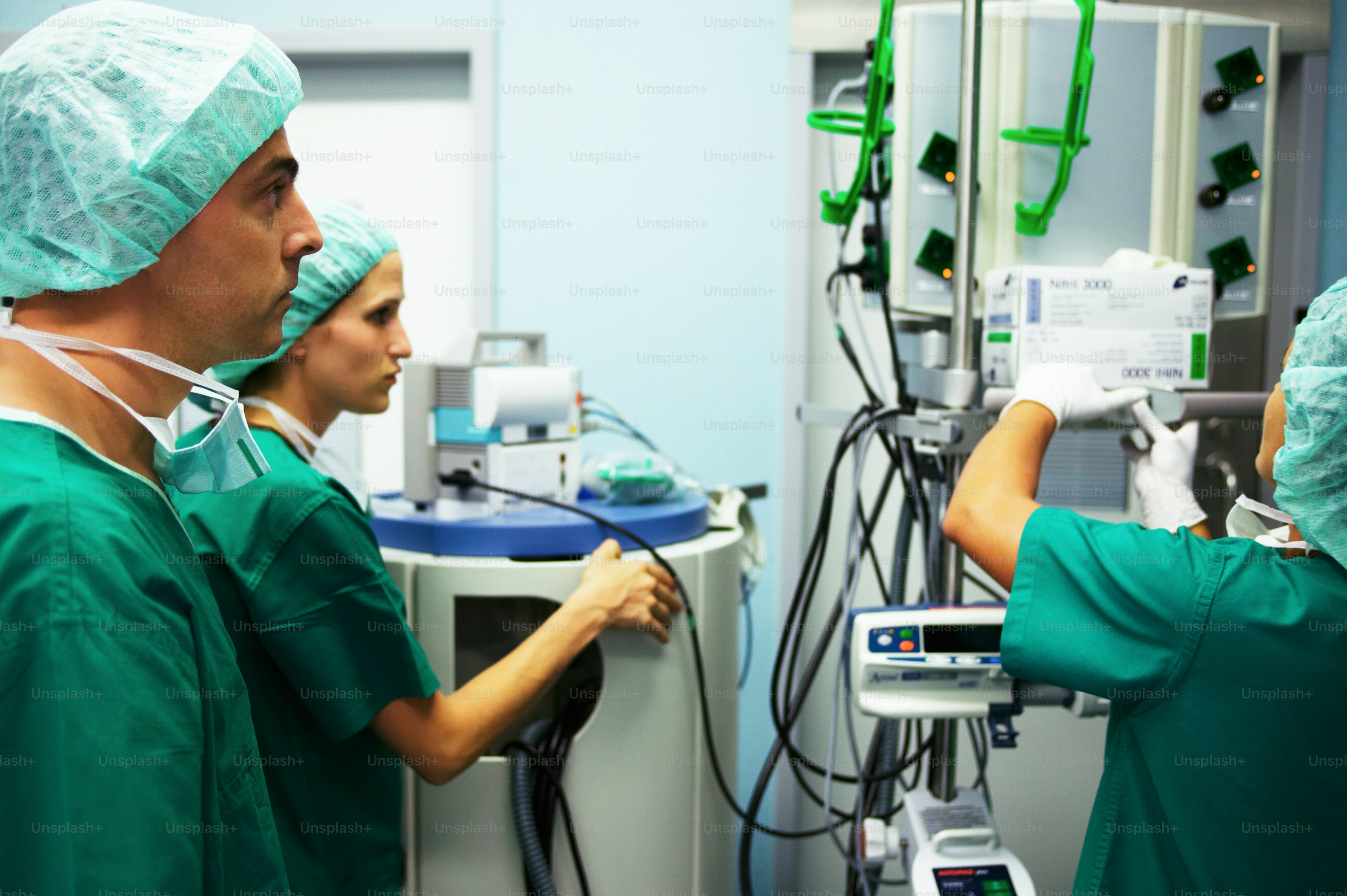 A couple of doctors in scrubs working on a machine photo – Rear view ...