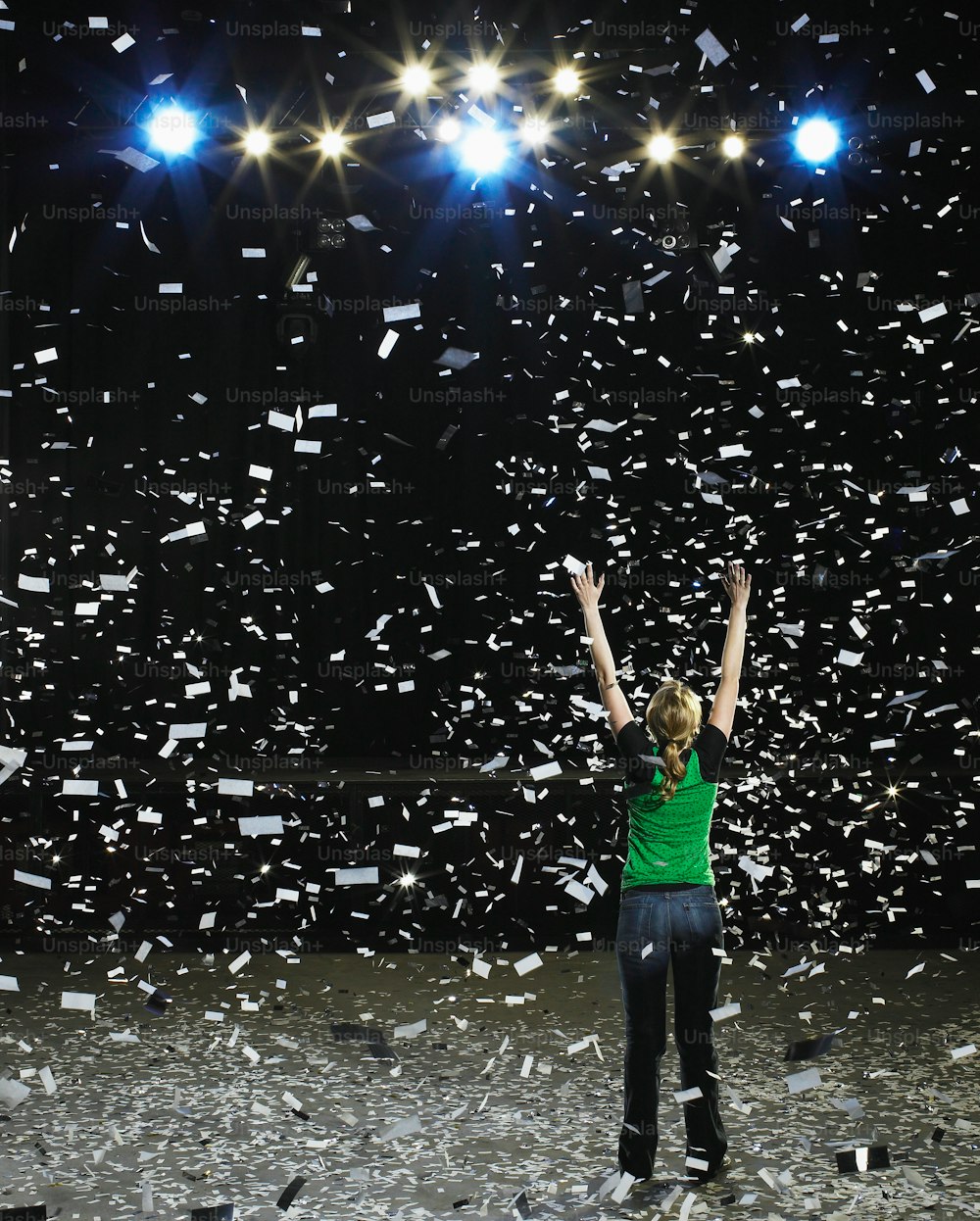 uma mulher em pé em um palco com os braços no ar
