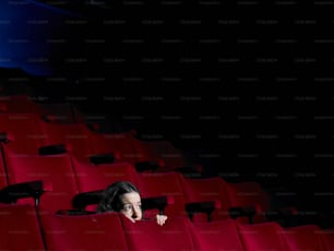 a woman peeking out from behind a row of red chairs