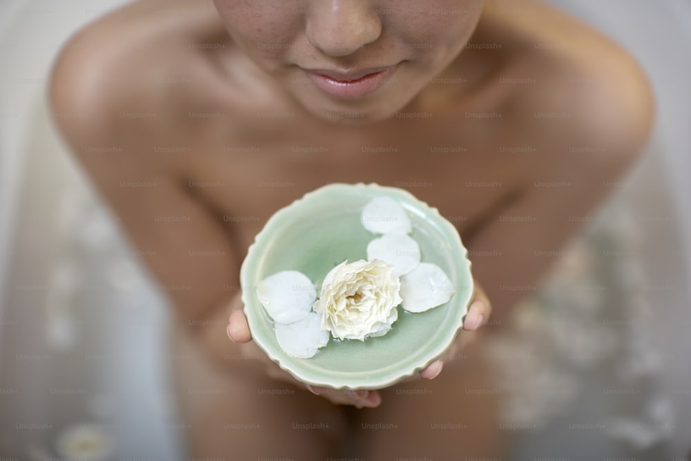 a woman holding a bowl with flowers in it