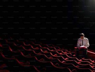 um homem de gravata sentado em um teatro