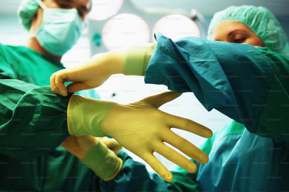 Un groupe de chirurgiens en gommages verts mettant des gants