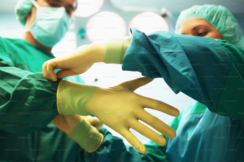 手袋をはめる緑のスクラブの外科医のグループ