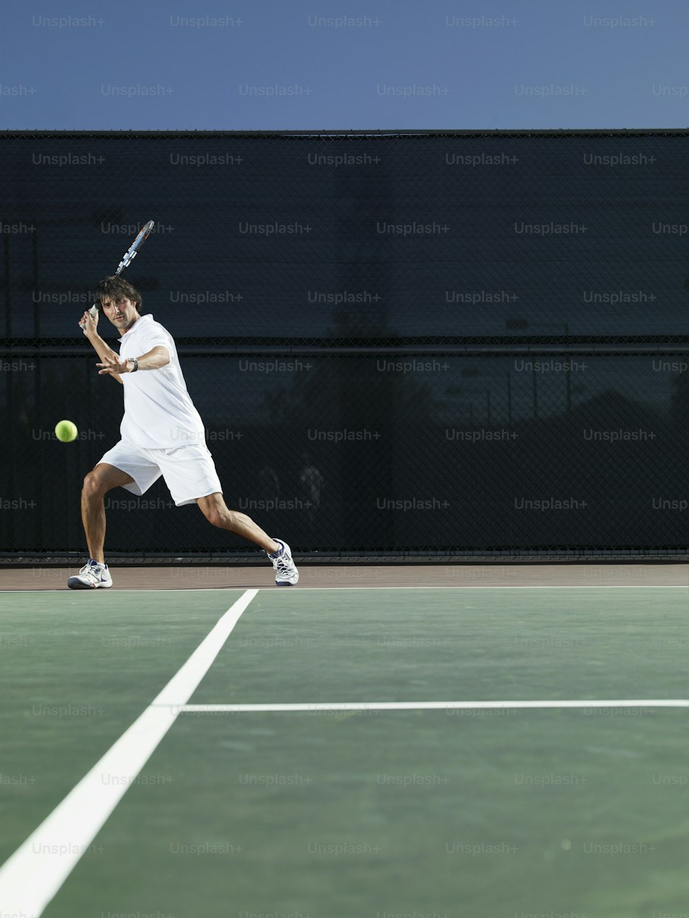 a man in white shirt and shorts playing a game of tennis