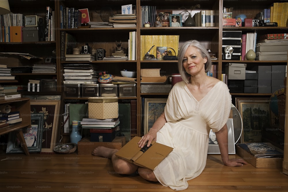 a woman sitting on the floor in front of a bookshelf