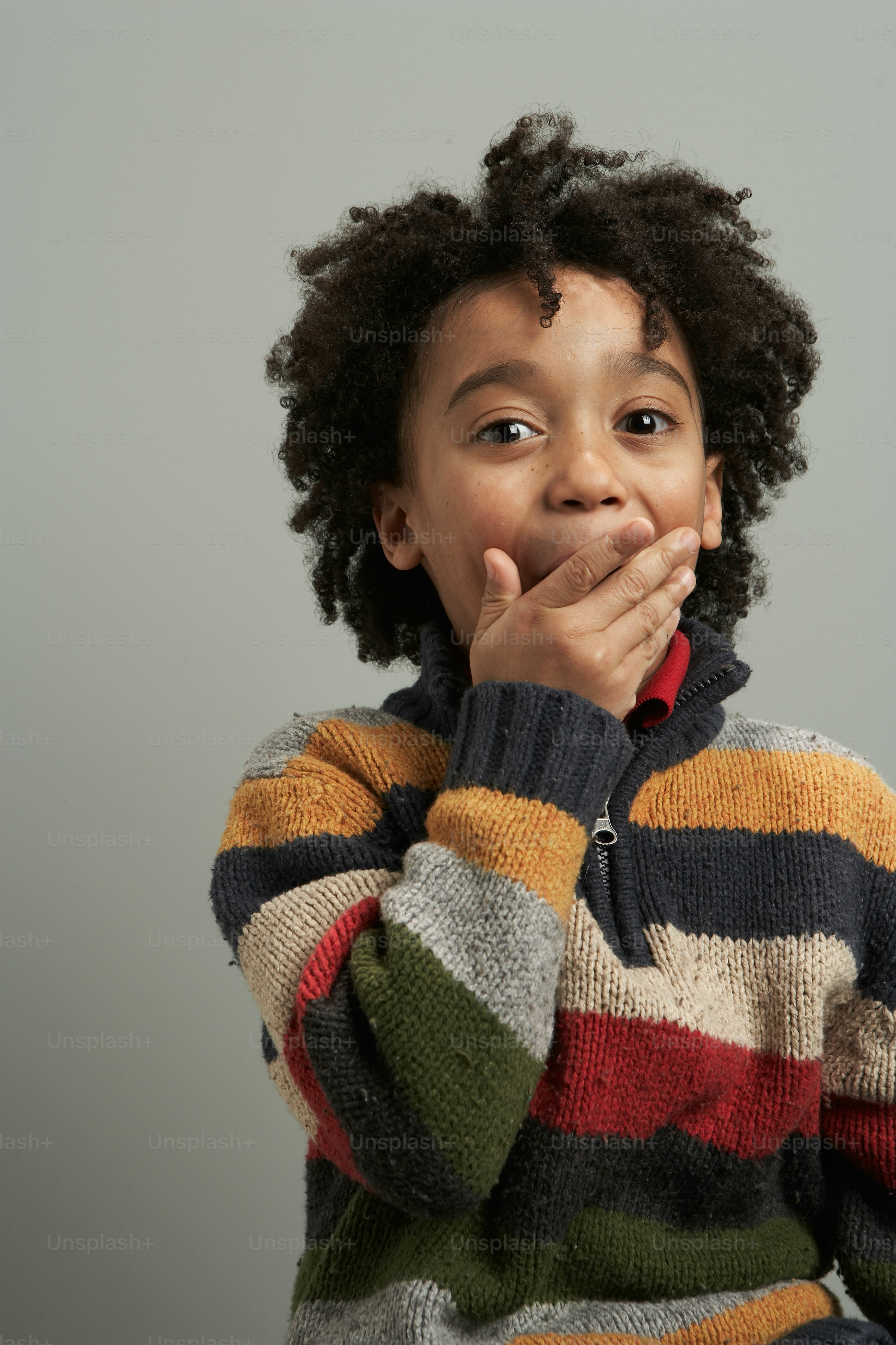 A young boy covers his mouth with his hands photo – Black boy Image on ...