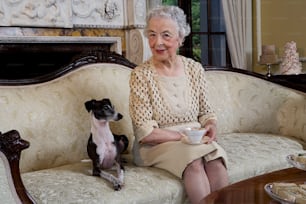a woman sitting on a couch next to a dog