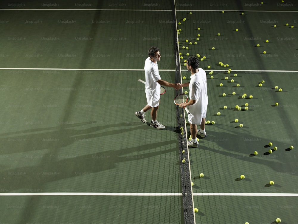 two tennis players shaking hands over a racket