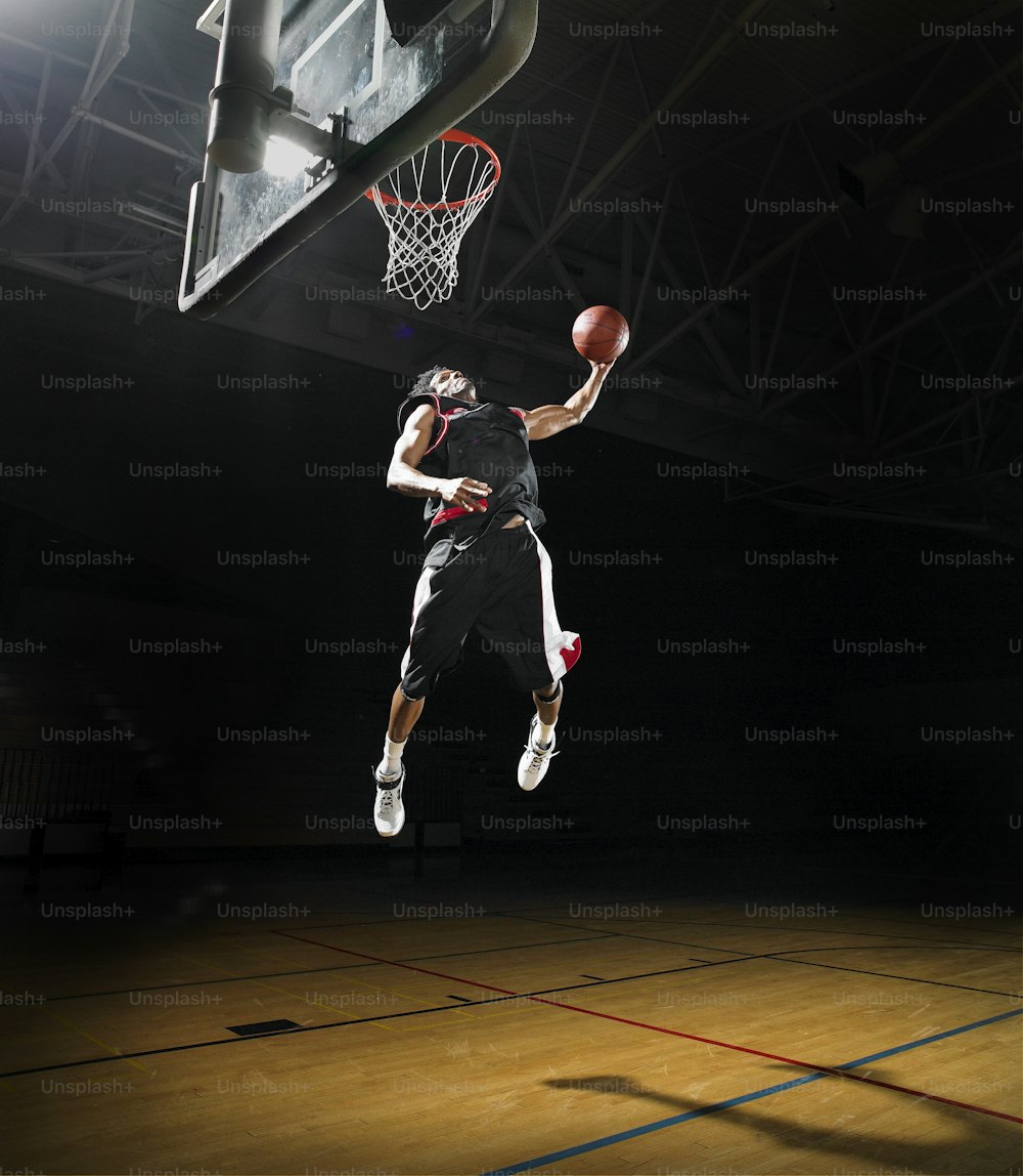 バスケットボールをダンクするために空中に飛び上がる男