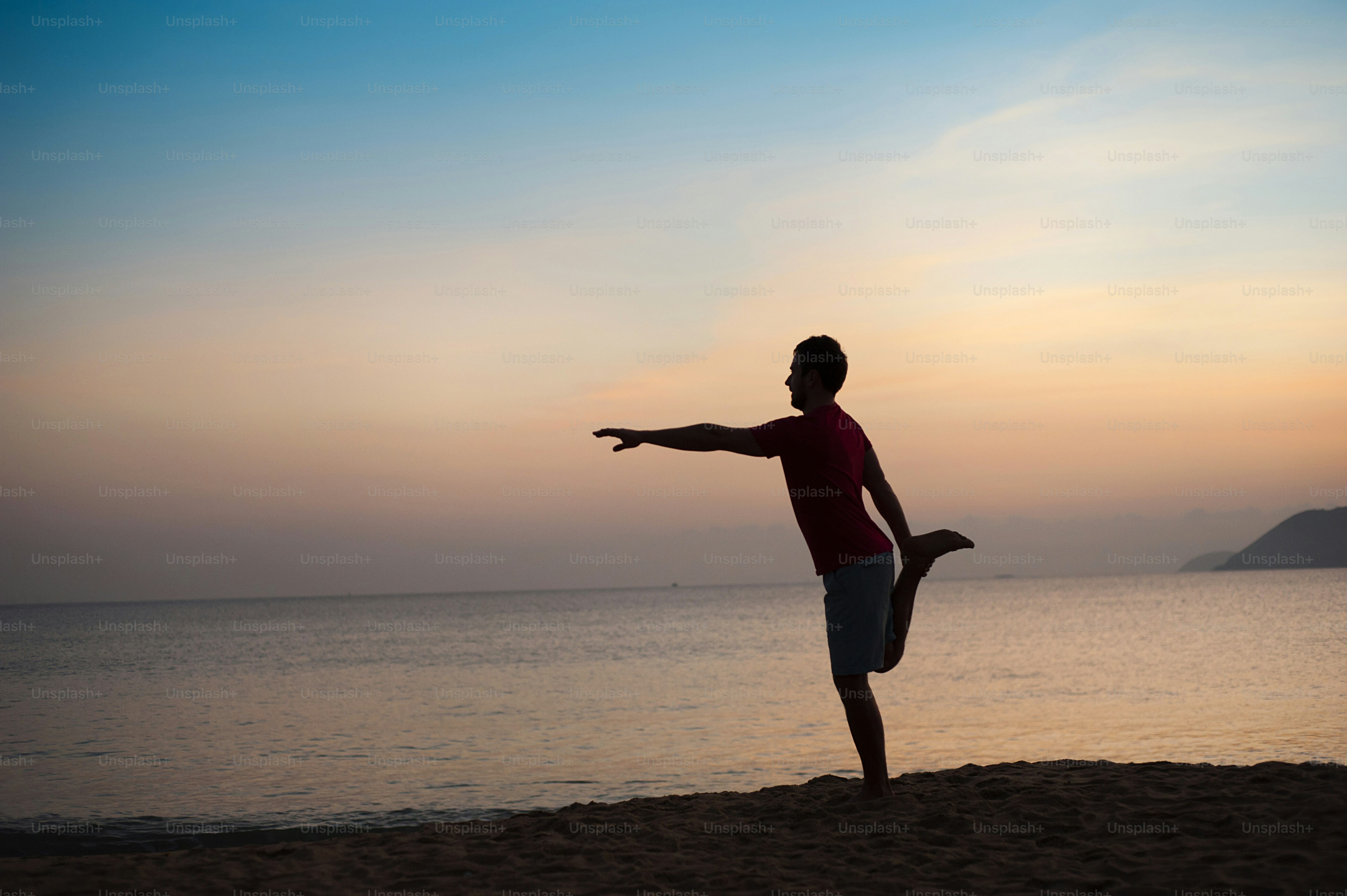Silhouette of sport active man running and exercising on the beach at sunset.
