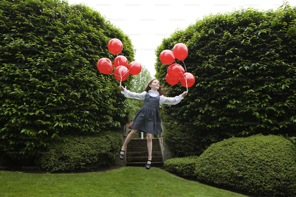 a woman in a dress is holding red balloons