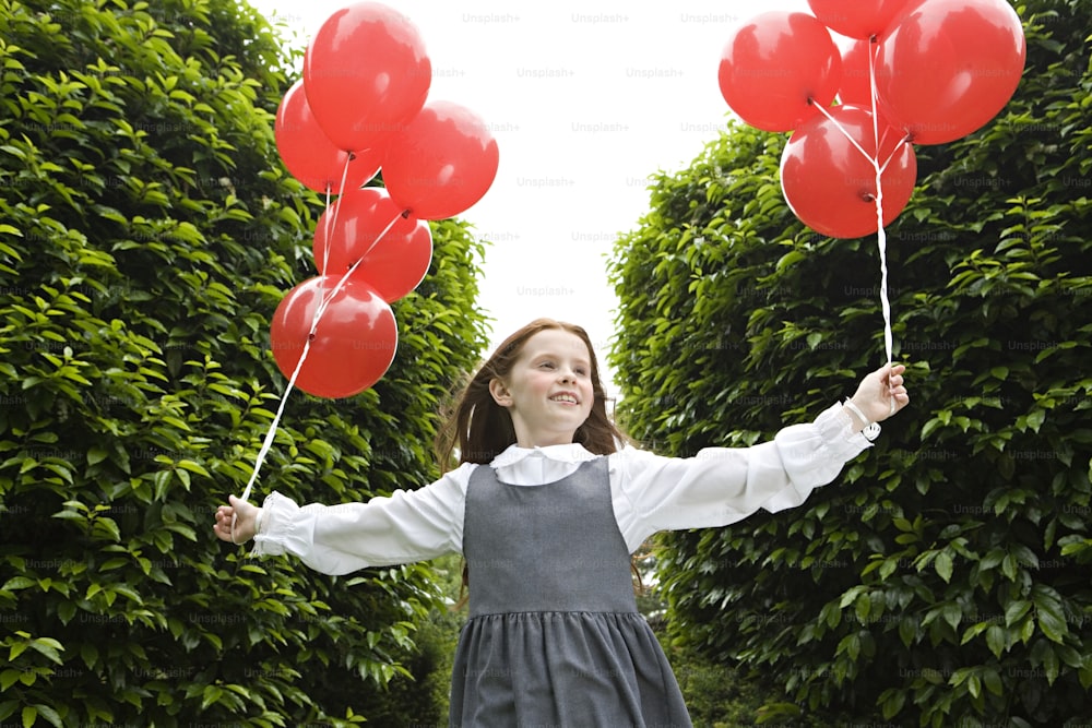 a young girl holding red balloons in her hands