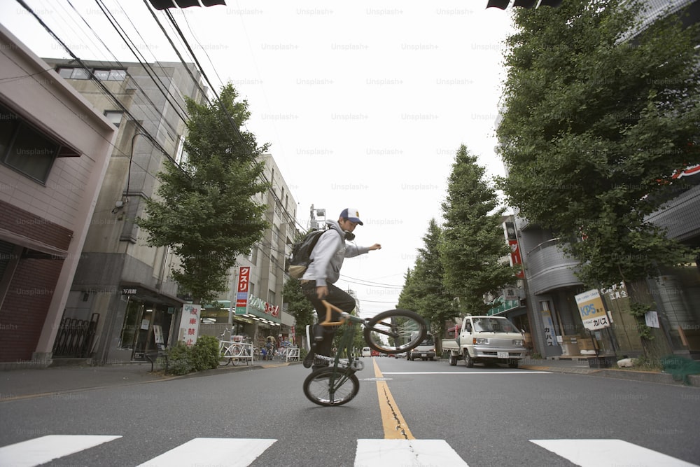 a man riding a bike down a street next to tall buildings