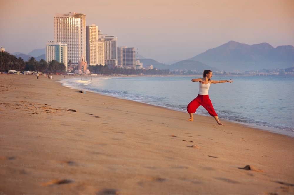 Femme sportive, active, étirements et exercices à la plage de la ville.