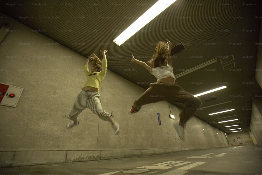Zwei Frauen springen in einem Parkhaus in die Luft