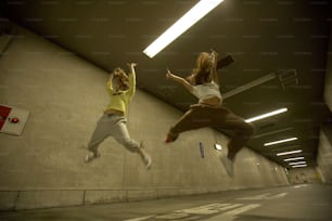two women jumping in the air in a parking garage