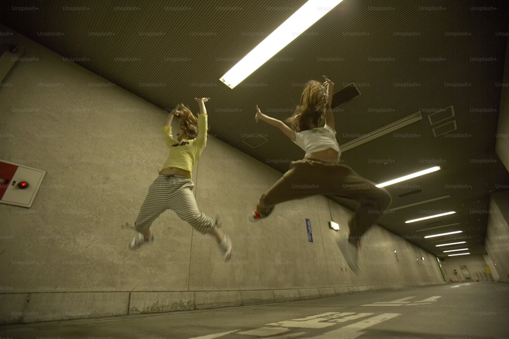 two women jumping in the air in a parking garage